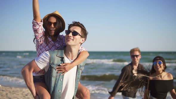 Couple Having Fun Doing Piggyback Together with Young Group of People Laughing Happy Joyful and