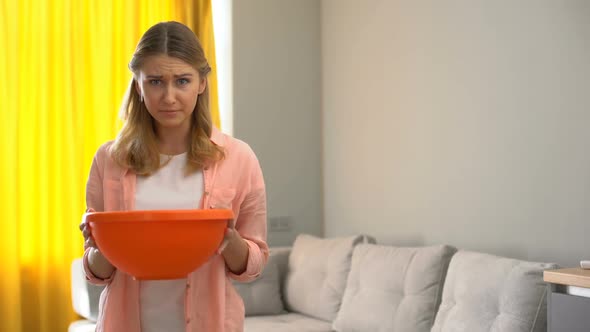 Upset Woman Holding Pot While Water Leaking From Ceiling, House Needs Renovation