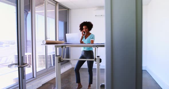 Female architect talking on mobile phone while working on blueprint over drafting table 4k