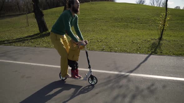 Adorable infant son riding on scooter in public playground, Zagreb, Croatia.