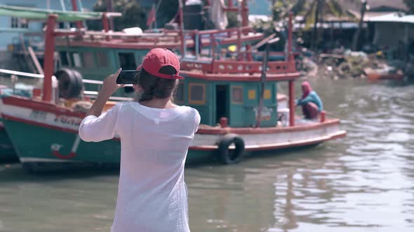 Girl with Dark Hair and Smartphone Against Fishing Boats