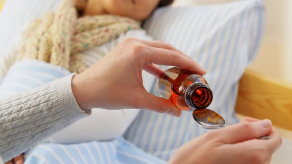 Mother Pouring Cough Syrup for Sick Daughter