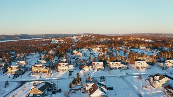 Scenic winter aerial flying over a snow covered neighbourhood in New Brunswick, Canada at sunset.