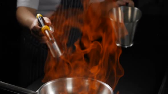 Slow Motion View of Big Fire Flame Over Frying Pan. Close Up. Hands with Gas Burner and Stainless