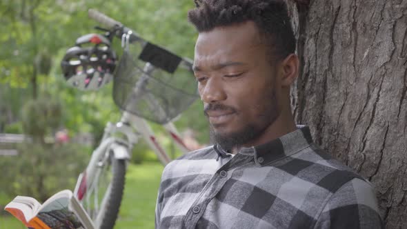 Portrait Confidient Cute Handsome African American Man Sitting Near His Bicycle Under an Old Tree in