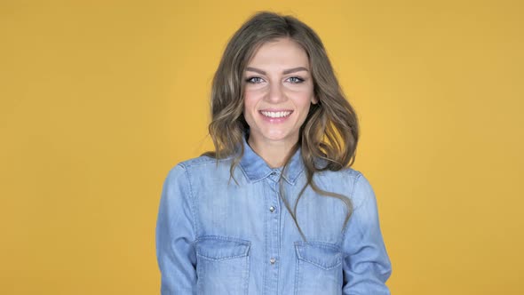 Young Girl Turning Around And Smiling Isolated on Yellow Background