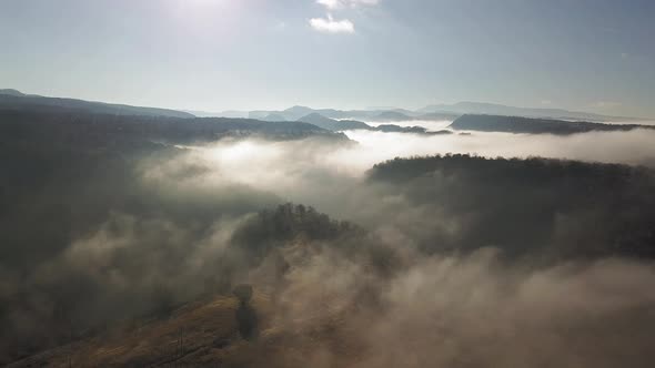 High flight above mountains and valleys covered with white carpet clouds with bright white sun rays