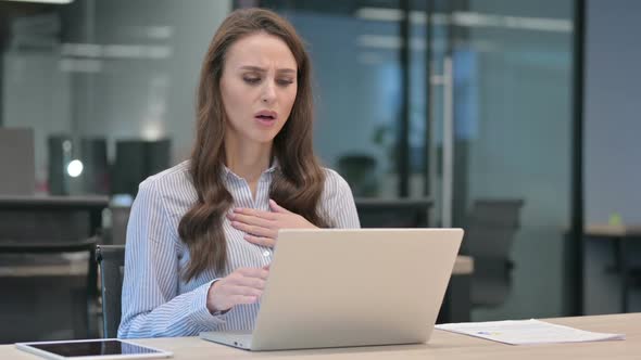 Young Businesswoman Coughing while using Laptop at Work