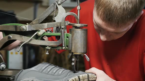 Caucasoid Male Shoemaker Sewing the Seam of a Sneaker with a Retro Typewriter