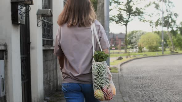 Young Woman Walking With Eco Bag On City Street
