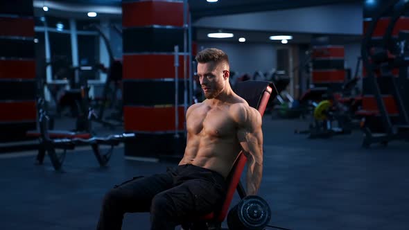 Handsome muscular man working out with dumbbells