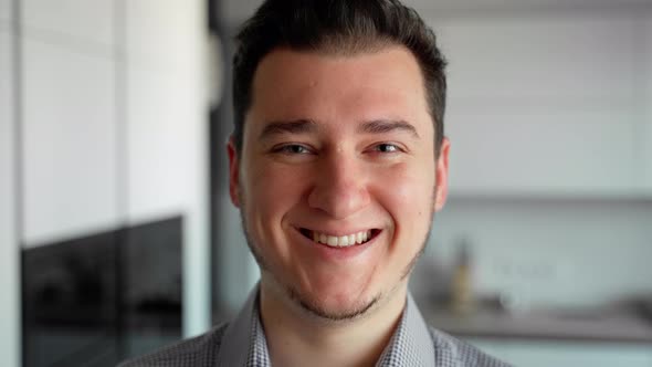 Portrait young adult man smiling. Indoors close up shot