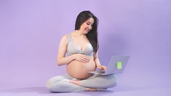 Pregnant Woman Working on Laptop While in Lotus Position