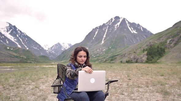 Woman Tourist with a Laptop, Prints, Works. Amid the Mountains Sitting on the Armchair