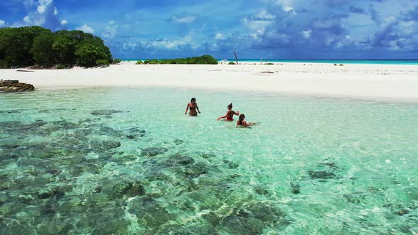 Young smiling ladies on vacation in the sun at the beach on sunny blue and white sand 4K background