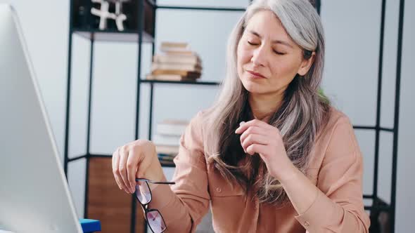 Overworked Mature Woman with Headache in Office