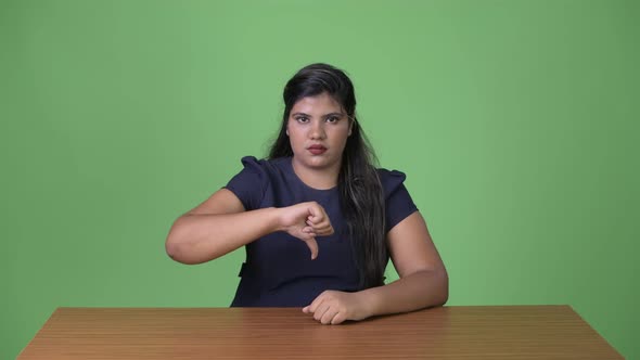 Young Overweight Beautiful Indian Businesswoman Against Green Background