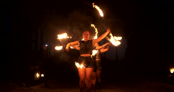 A Group of People with Fire and Torches Dancing at Sunset in the Hangar in Slow Motion