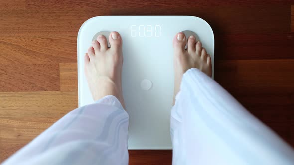 Crop woman standing on digital weight scales