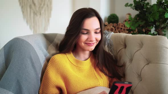 Woman Smiling Hold Smartphone Watching Social Media Stories Video Sit on Sofa