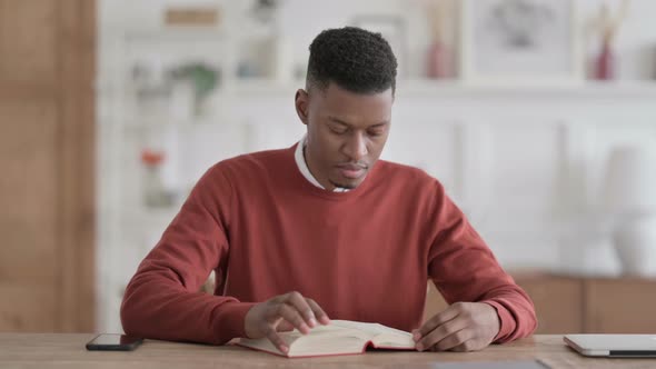 African Man Reading Book while Sitting in Office