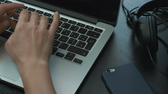 Close up of female hands typing on laptop computer keyboard at office workplace.