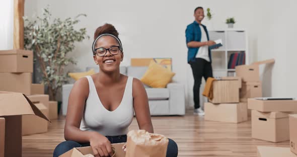 Happy Couple in Love Move Into a New Apartment the Woman Sits on the Living Room Floor and Unpacks