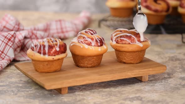 Pouring Icing Over Swirl Buns with Jam.