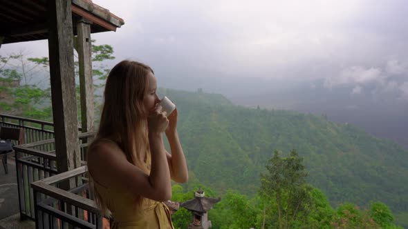 Slowmotion Shot of a Young Woman Drinking Tea or Coffee in a Cafe in the Mountains