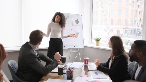 Confident African Female Trainer Giving Educational Workshop to Diverse Team at Office