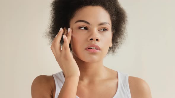 Black african american black woman applying moisturizing cream on her face