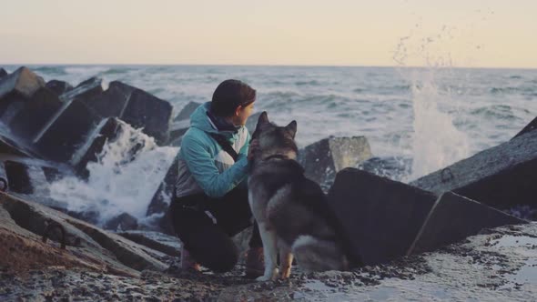 Young Beautiful Female Walking with Siberian Husky Dog on the Beach at Sunset Slow Motion