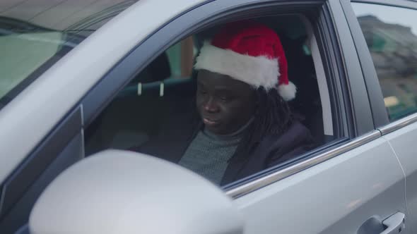 Handsome African American Man Giving a Christmas Gift Through the Window of His Car