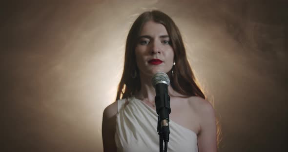 The Girl Singer Approaches the Microphone and Begins To Sing, the Scene in Smoke. Close Up V3