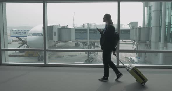 Woman with phone and luggage walking in Seoul airport, South Korea