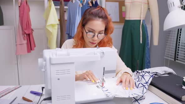 Asian beautiful tailor woman working on clothes in tailoring atelier.