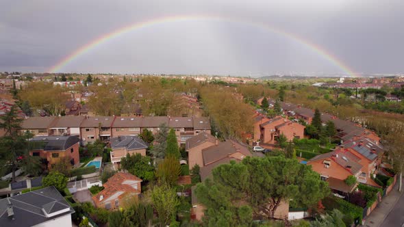 Full rainbow over homes in suburbs, Puzuelo de Alarcon, Madrid, Spain. Fly over