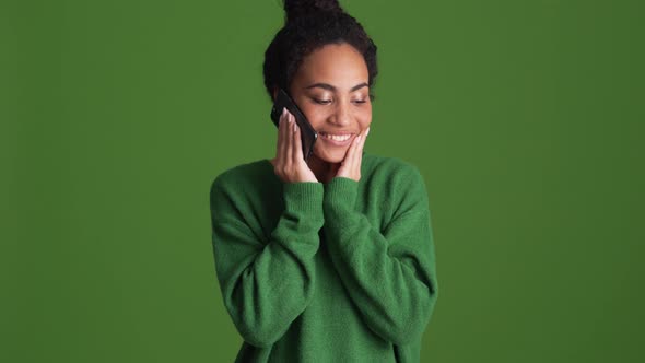 Happy African woman in green shirt talking by phone