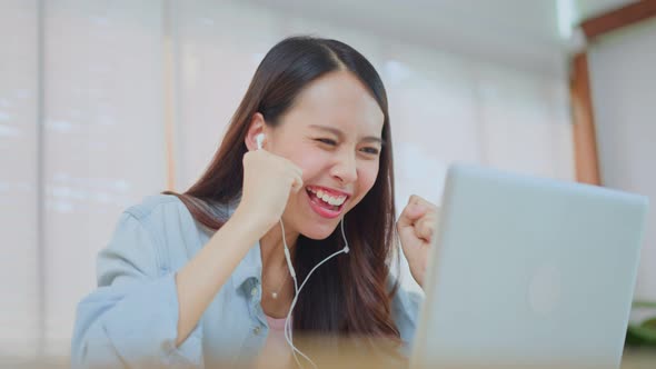 Asian attractive girl student winner feel happy after found out good news on laptop then celebrate.