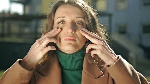 Portrait of a Woman Painting Yellow and Blue Stripes on Her Cheeks