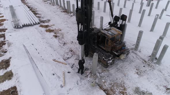 Aerial drone view of a pile bore machine at work at winter construction site 10