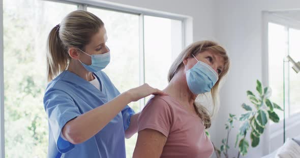 Female health worker stretching neck of senior woman at home