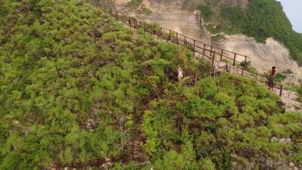 Tourist walking down the stairs overgrown with tropical bushes, aerial dolly out shot . Extreme terr