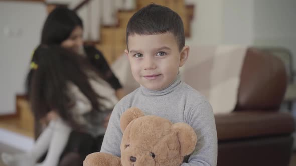 Smiling Middle Eastern Boy with Grey Eyes and Dark Hair Holding the Teddy Bear and Looking