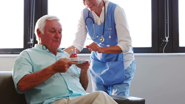 Senior man blowing candles out with nurse