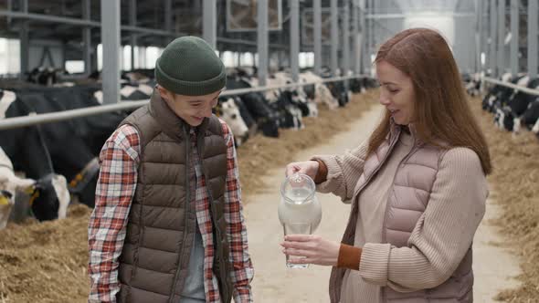 Woman Pouring Fresh Milk for Teenage Boy at Farm