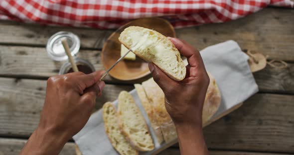 Video of slice of bread in hands on wooden worktop seeing from above