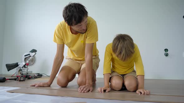 Father and His Little Son Install Laminate on the Floor in Their Apartment