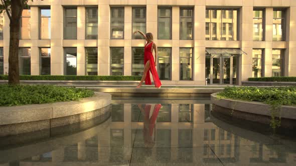 Beautiful Young Girl Dancing on the Street of a Modern City and Is Reflected in the Water