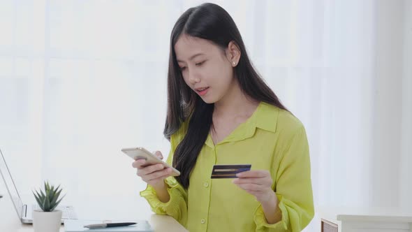 Young asian business woman using smart phone and holding credit card while online shopping.